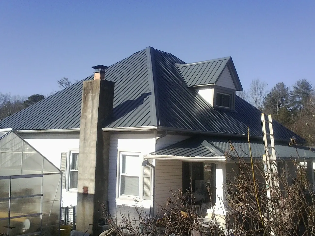 Dark blue standing seam metal roof on a white farmhouse with dormer — Slate & Tile Roof Repair by Roofing Brothers in Moseley