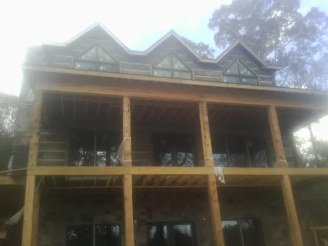 Dormers and porch framing on a large log home under construction — Roof Coating work by our crew in Moseley