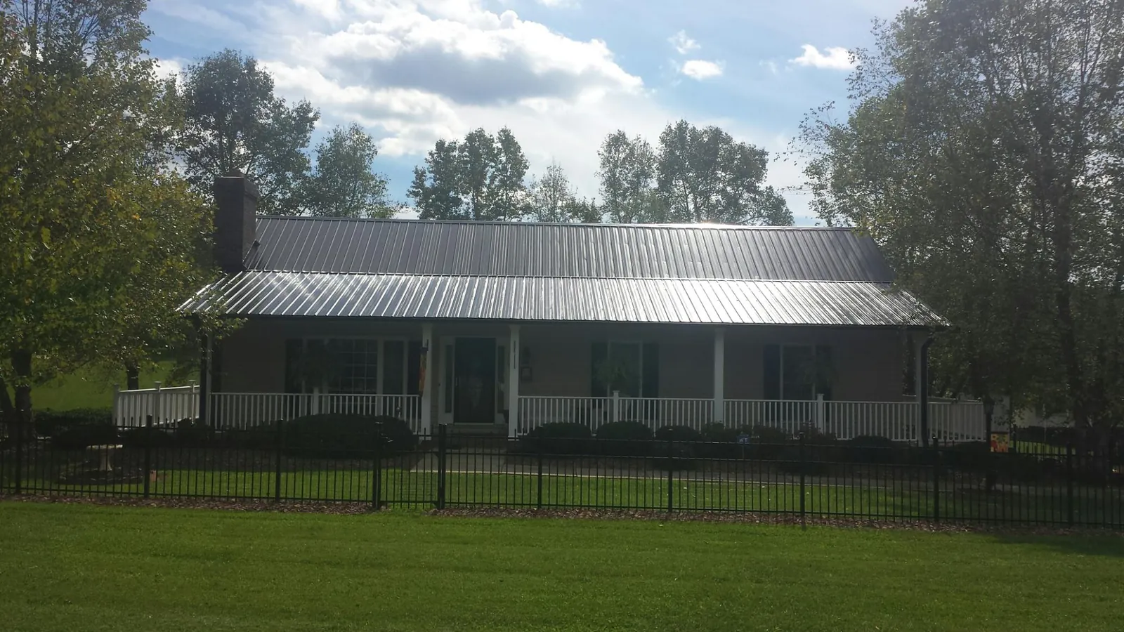 Gray metal roof on a brick ranch with a full width front porch — Gutter Guard Installation work by our crew in Moseley