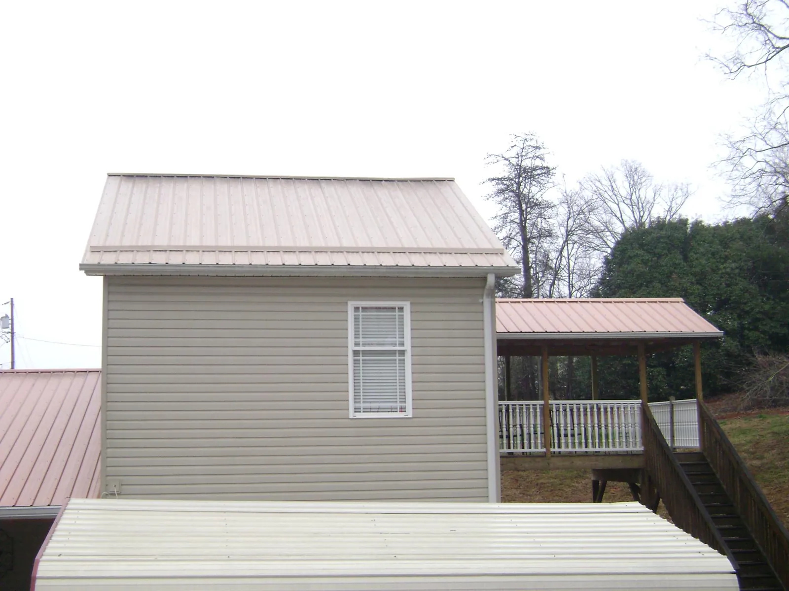 Tan metal roofs on a two story addition and attached porch, from a Roof Replacement job in Moseley