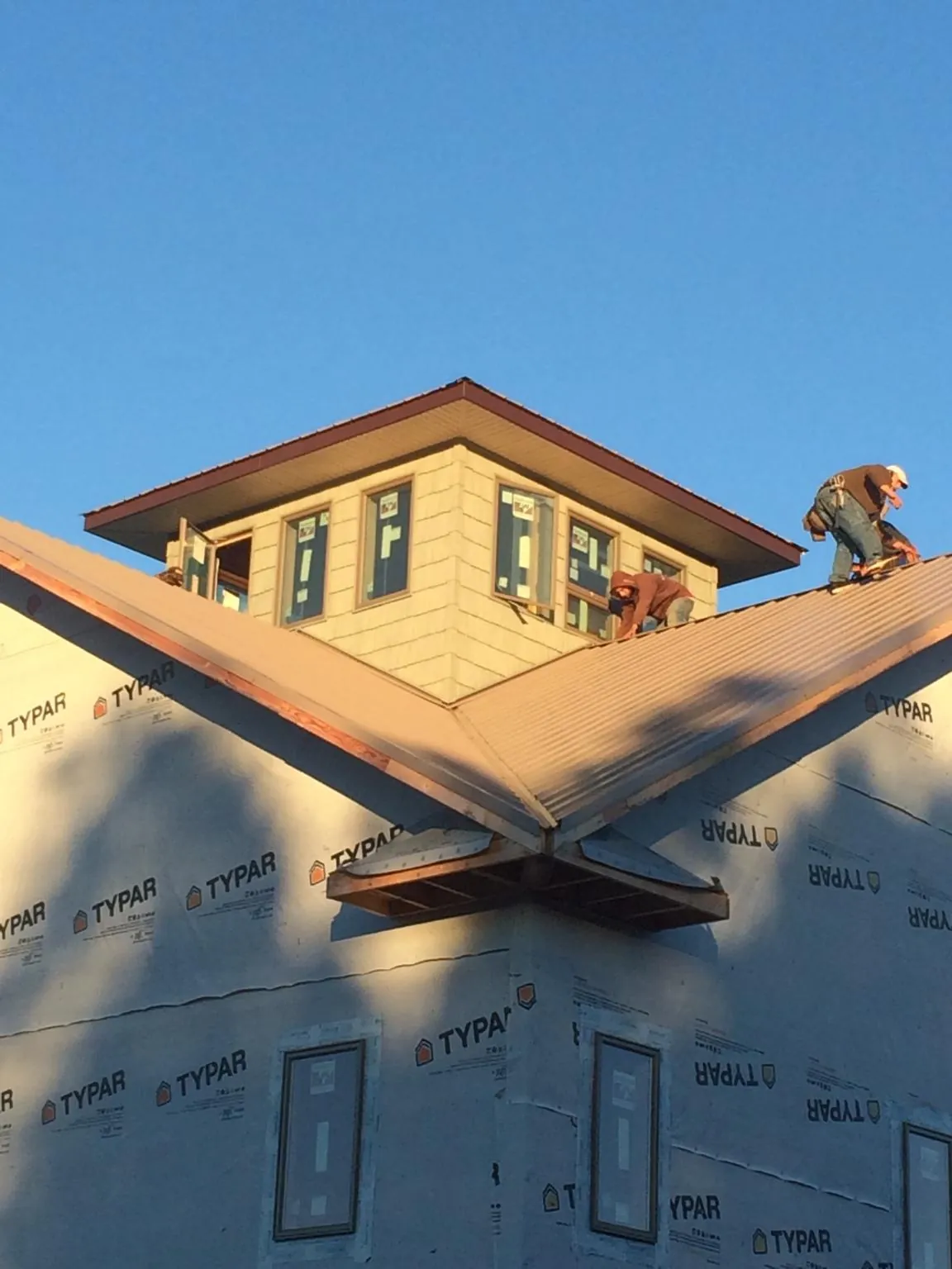 Roofers working around a rooftop cupola on a new metal roof at sunset — Roof Waterproofing in Moseley by Roofing Brothers